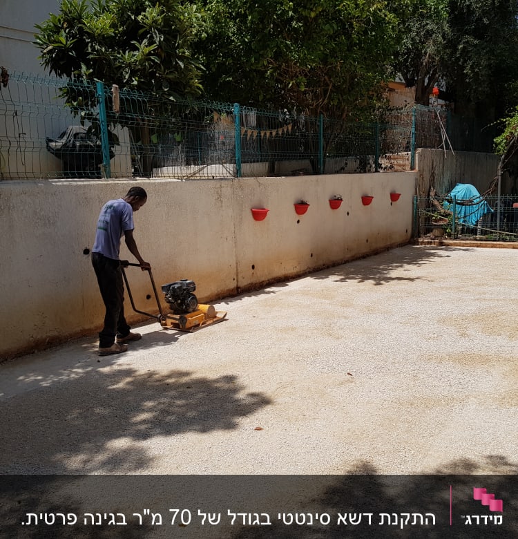 אדם מפעיל מכבש על קרקע בגינה